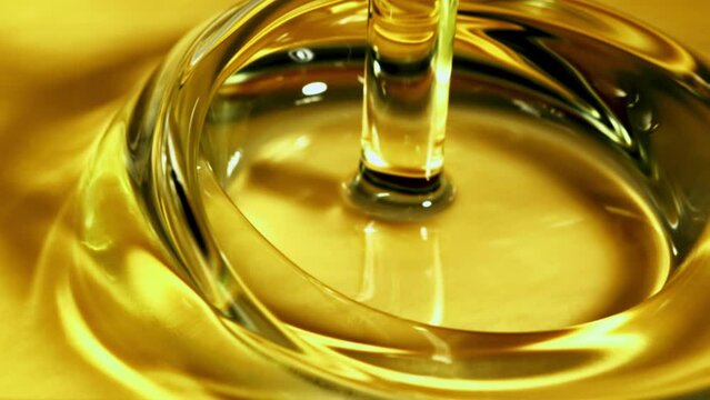 A jet of olive oil falls with splashes. Macro background. Filmed on a high-speed camera at 1000 fps. 