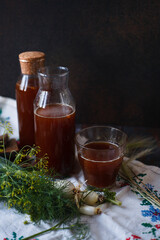Bottles and a glass of homemade kvass and slices of rye bread with fresh green onion and dill on...