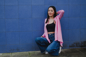 smiling young woman squatting on wall