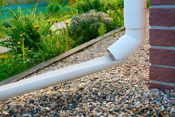 Plastic extension of the drain from the roof directing water away from the foundation of the house.