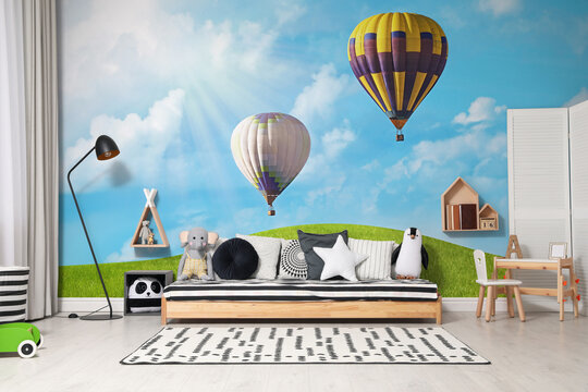 Beautiful wallpaper with image of hot air balloons in sky with clouds over green meadow in child's room