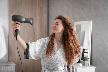 Beautiful woman using hair dryer in bathroom