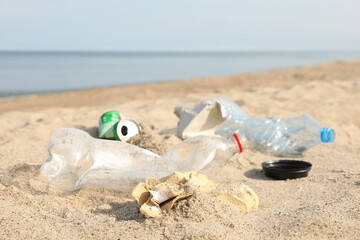 Fototapeta na wymiar Garbage scattered on beach near sea, closeup. Recycling problem
