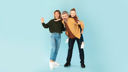 Obraz premium Happy Parents And Daughter Posing Waving Hello Over Blue Background
