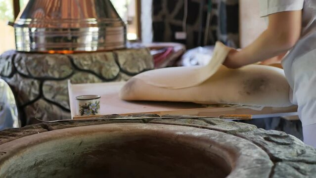 the process of cooking and baking in tonir Armenian national pita by women bakers. The baker takes out the baked hot pita bread from the tandoor. Close-up, DOF.