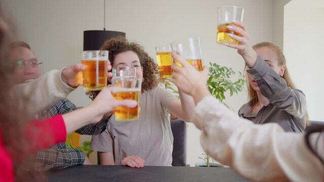 Celebration beer cheers concept, hands holding up bottles beer people group in outdoor party vacation. Slow motion close up happy young friends having fun together drinking beer clinking glasses pub.