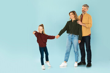 Obraz premium Daughter Holding Hands With Parents Pointing Finger On Blue Background