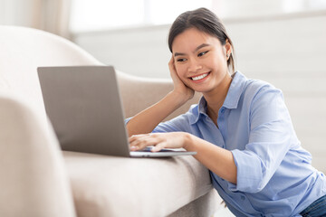 Closeup of smiling asian lady typing on notebook keyboard