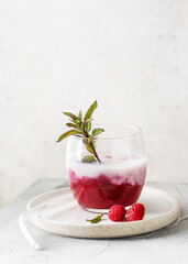 Homemade buttermilk smoothie with raspberry jam with peppermint branch in a glass. Healthy sweet food concept Copy space.