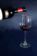 Red wine pouring into a wine glass. Smoke background with grey tonation.