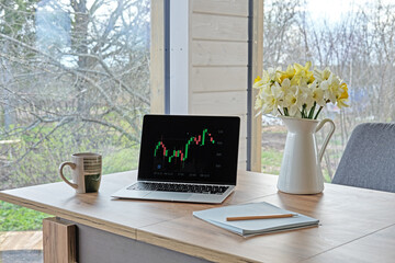 Laptop with financial chart on the screen. Modern workplace of financial analyst at home. Financial planning.