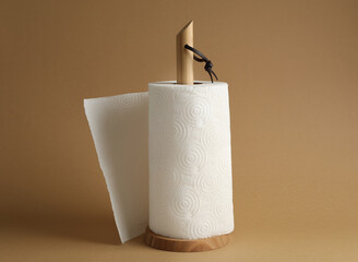 Holder with roll of white paper towels on brown background