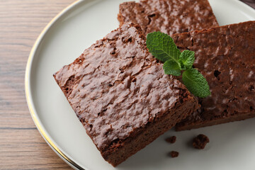 Delicious chocolate brownies with fresh mint on wooden table, closeup