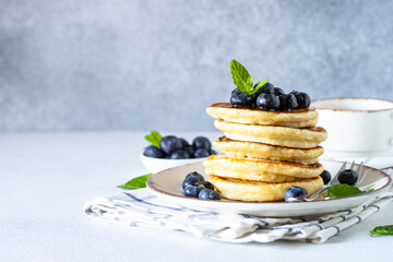 Pancakes with fresh blueberries and honey at white table.