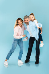 Fototapeta premium Vertical Shot Of Happy Family Posing Together On Blue Background