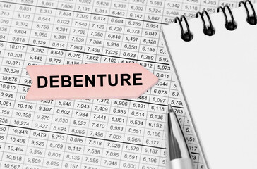 Fototapeta premium On the table among the reports is a notebook, a pen with an arrow with the inscription - Debenture