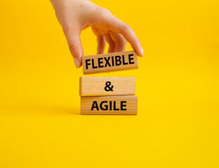 Flexible and agile symbol. Concept word Flexible and agile on wooden blocks. Beautiful yellow background. Businessman hand. Business and Flexible and agile concept. Copy space