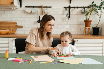 Mother and little daughter enjoy a creative morning by making crafts for kindergarten.