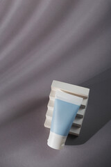 White blue mockup tube on grey background with shadows, harsh light and white concrete decor. Mineral tooth paste template, sunscreen cream, balm or body lotion. No brand