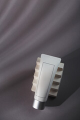White mockup tube on grey background with shadows, harsh light and white concrete decor. Mineral tooth paste template, sunscreen cream, balm or body lotion. No brand