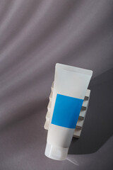 White blue mockup tube on grey background with shadows, harsh light and white concrete decor. Mineral tooth paste template, sunscreen cream, balm or body lotion. No brand