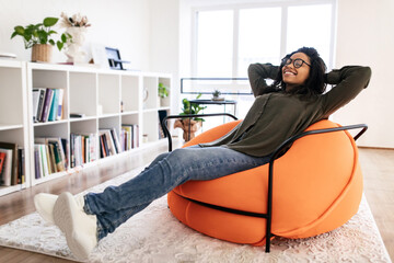 Calm black woman having rest at home on the couch - obrazy, fototapety, plakaty
