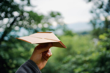 Brown paper plane outdoor representing green and sustainable flying. Space for text.	