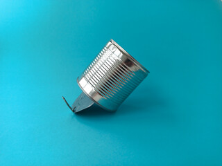 An empty metal shiny tin can is lying on a blue background. The concept of ecology. Recycling of garbage.