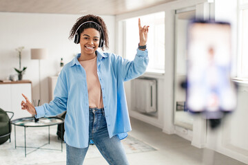 Cheerful black woman filming dance video on cell phone