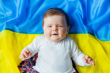 Little infant girl lying on ukrainian flag. Top view