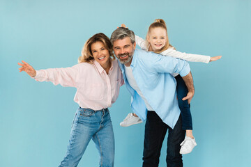 Joyful Middle Aged Parents And Little Daughter Posing, Blue Background