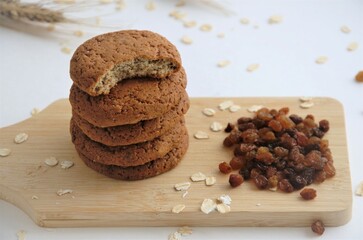 biscuits on a wooden board next to raisins and raw oatmeal, the concept of oatmeal biscuits with raisins