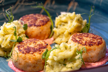 Salmon cutlets in a creamy sauce with tobiko caviar and mashed potatoes, sprinkled with fresh herbs.