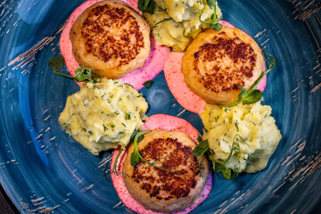 Salmon cutlets in a creamy sauce with tobiko caviar and mashed potatoes, sprinkled with fresh herbs.