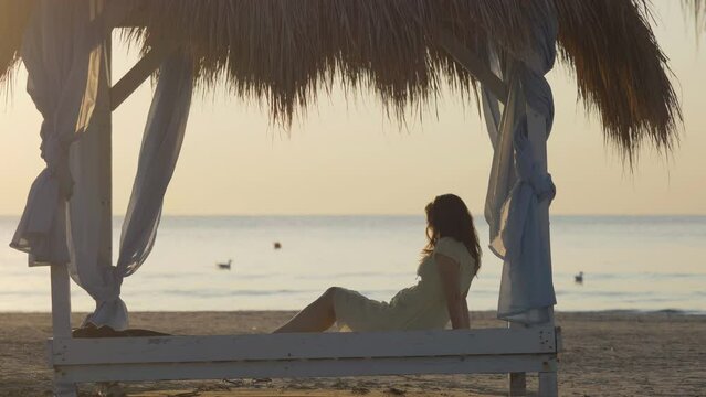 Young woman sit on canopy admiring sea, summer evening