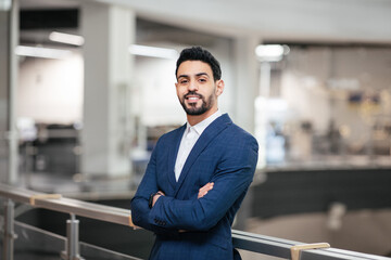 Smiling confident calm attractive young middle eastern businessman with beard in suit with crossed arms - Powered by Adobe