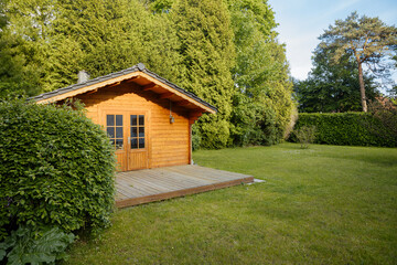 Small cottage in the countryside. Garden house made of wood. Cottage in your own garden for hobbies and free time during the pandemic. Shed in a large garden in Germany - obrazy, fototapety, plakaty