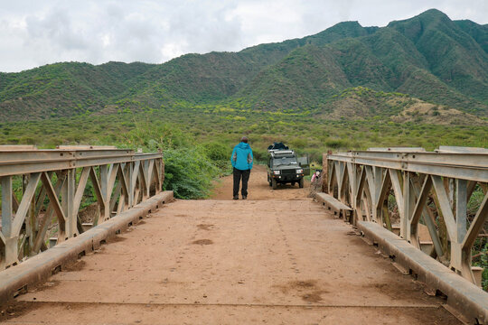Rear view of a man on the bridge standing next to a safari van against Shompole Hill in Kajiado, Kenya
