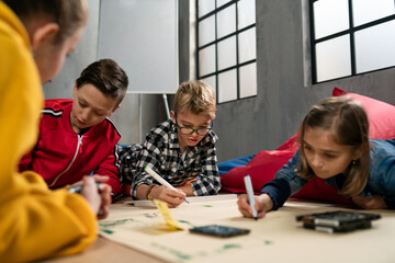 Group of happy kids with their teacher working on project together at classroom.