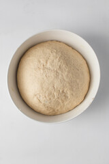 Fototapeta na wymiar Dough that has doubled in size, dough that has risen, proofed dough in a white bowl