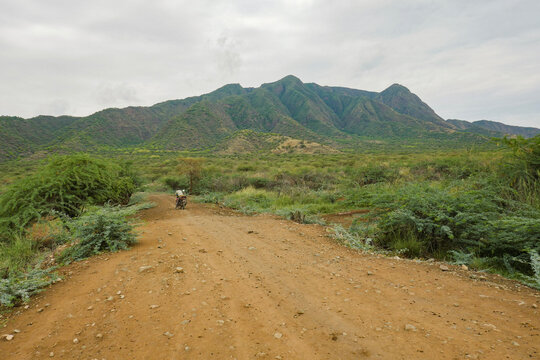 A man on a motorcycle against a mountain background at Shompole Conservancy, Kajiado County, Kenya