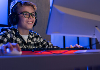 Young gamer boy with headphones playing computer video game. © Halfpoint