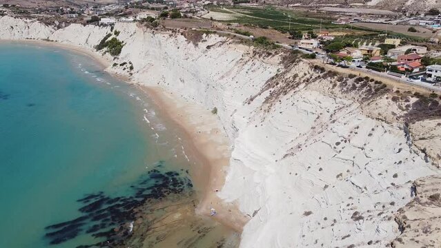 Aerial view of white rocky cliffs at Scala dei Turchi, Sicily, Italy, with turquoise clear water. Drone shot of the limestone rock formation and beach. Tourist attraction, travel holiday scenery.