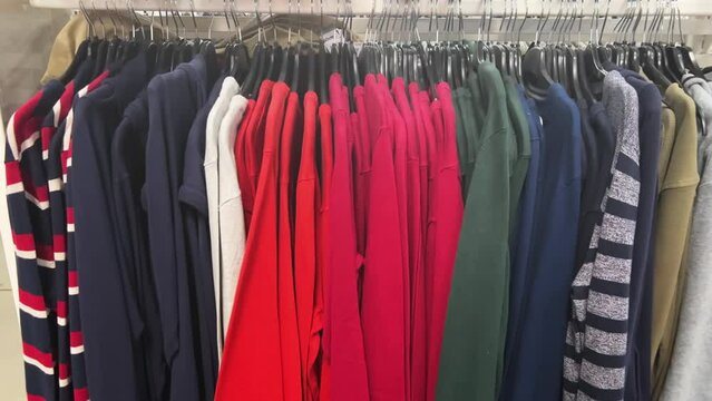 Multicolored pullovers hanging on hangers in a casual clothing store