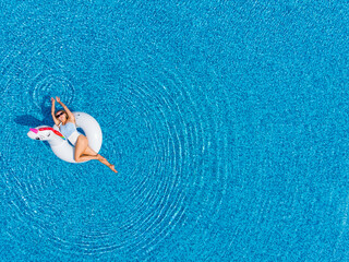 Woman on unicorn pool float in pool in hotel. Summer holidays, enjoying summer vacations during quarantine. Aerial top view from drone