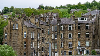 The cottages built of local sandstone and gritstone, with dressed stone surrounds to the doorways and mullioned windows in characteristic Pennine style.