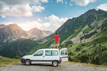 Young man enjoying nature on top of his camper van.