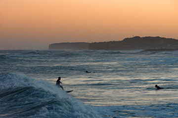Fototapeta premium Man surfing a wave at orange sunset