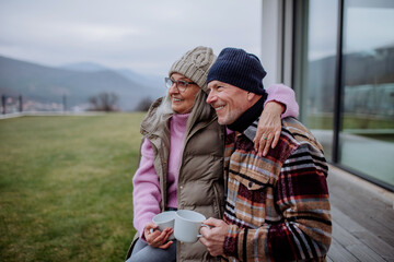 Happy senior couple sitting on terrace and drinking coffee together.