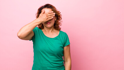 middle age hispanic woman covering eyes with one hand feeling scared or anxious, wondering or...